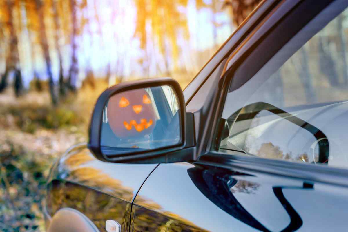 A new car with the reflection of a jack-o-lantern in the rearview mirror