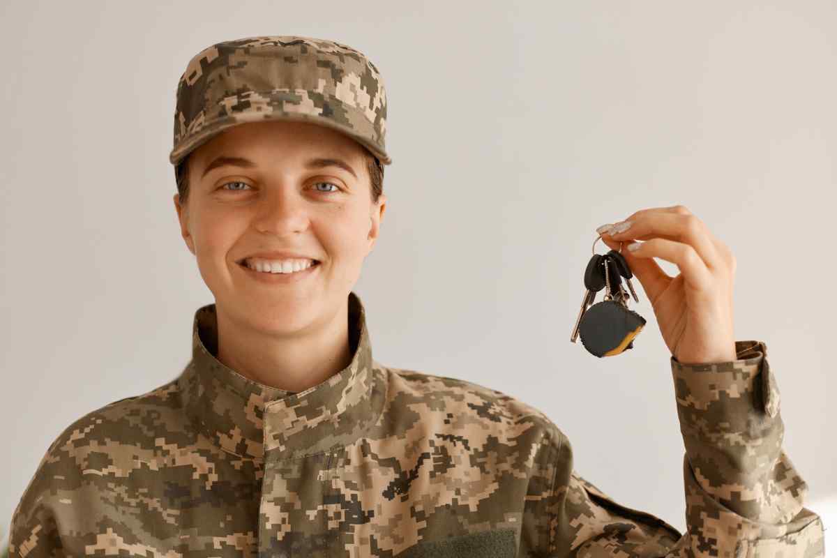 A military woman smiles as she holds up the keys to her new vehicle