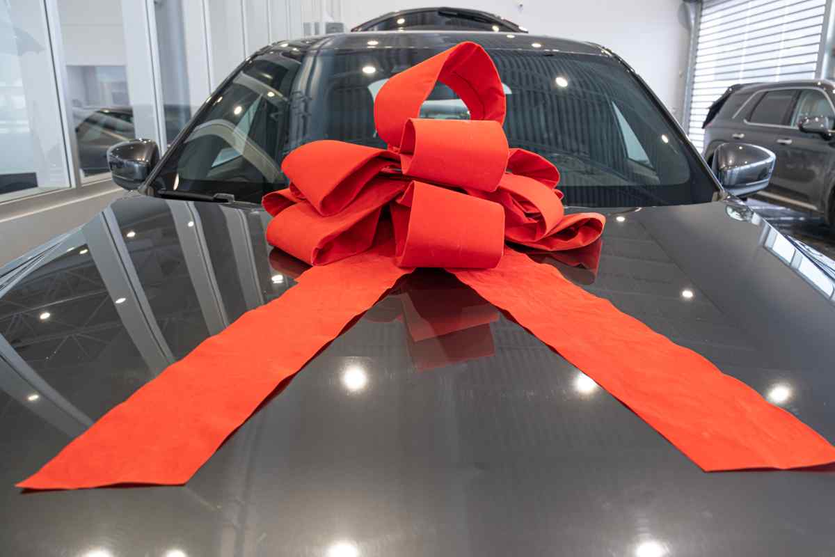 A new car with a giant, red Christmas bow on the hood