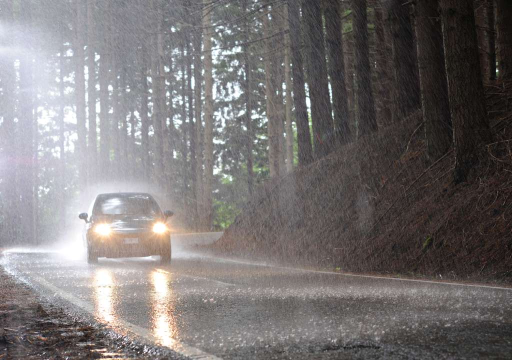 A car drives safely down the road during an April shower