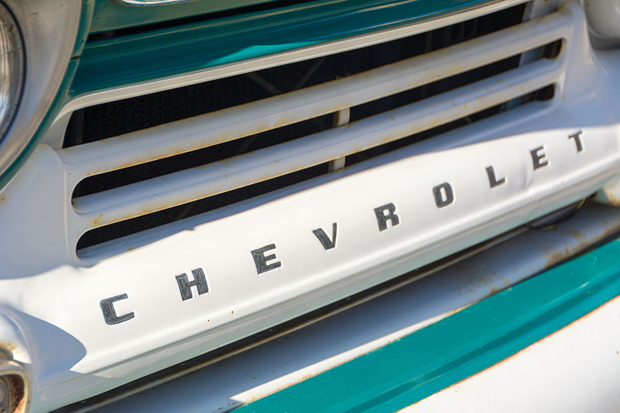 The bumper of a teal truck which reads Chevrolet