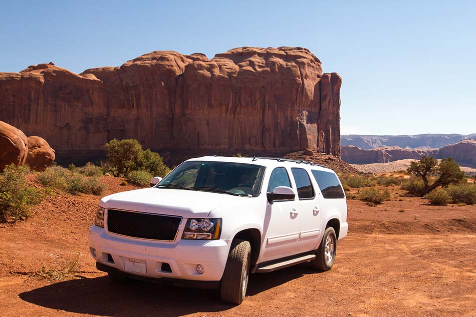 A new, white Chevy SUV parked in Monument Valley