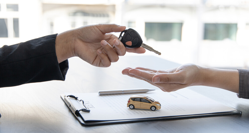 A salesperson hands car keys to a business owner